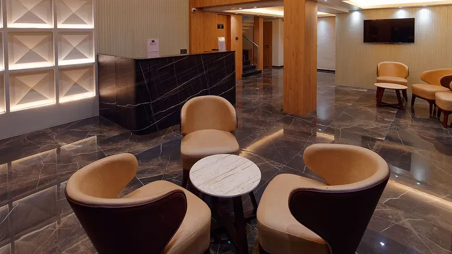 Lobby with seating chairs and light hanging from the ceiling Side view of twin beds with a television in font and ceiling on the wall at Ankit Hotel, Jabalpur