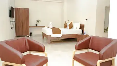 Well-lit room with a double bed and chairs at ANS M Square Hotel & Resort, Kalaburagi