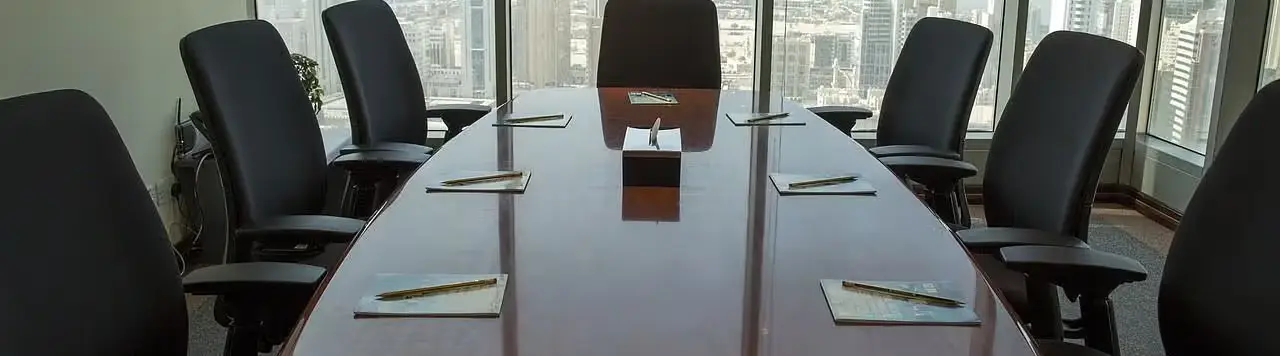 Board room with well arranged chair and notepad on the table.