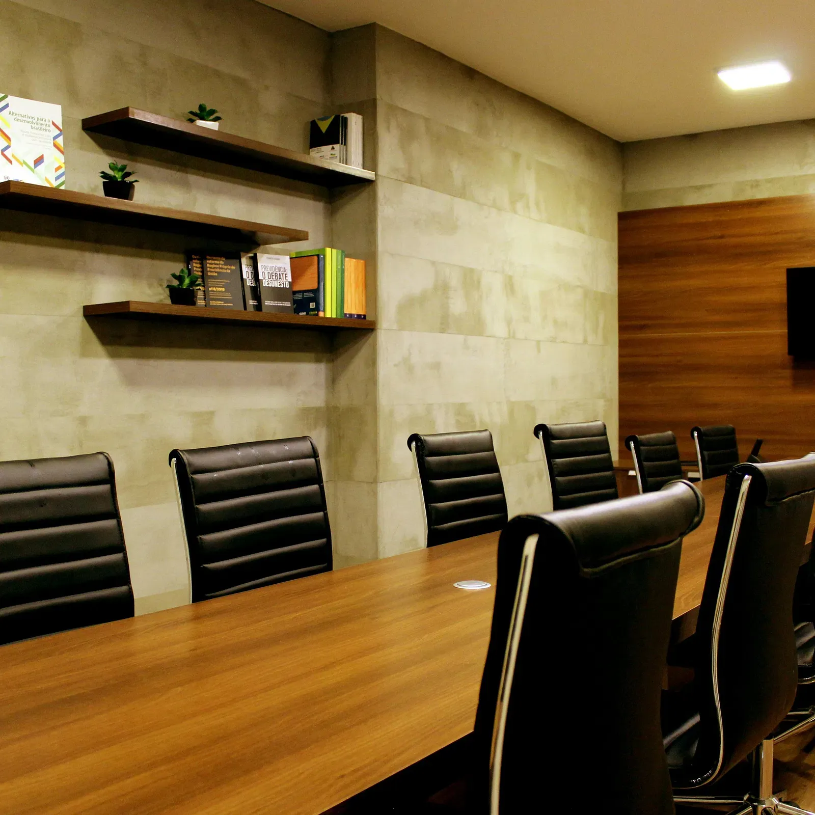 A conference hall setup with office chairs and a long, wooden table